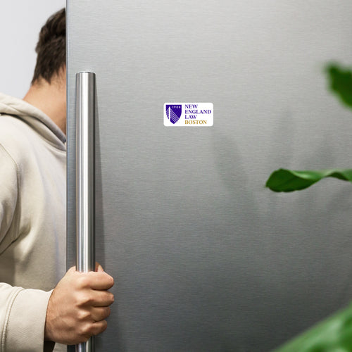 Person holding a silver refrigerator with a sticker with 'New England Law Boston' printed on it